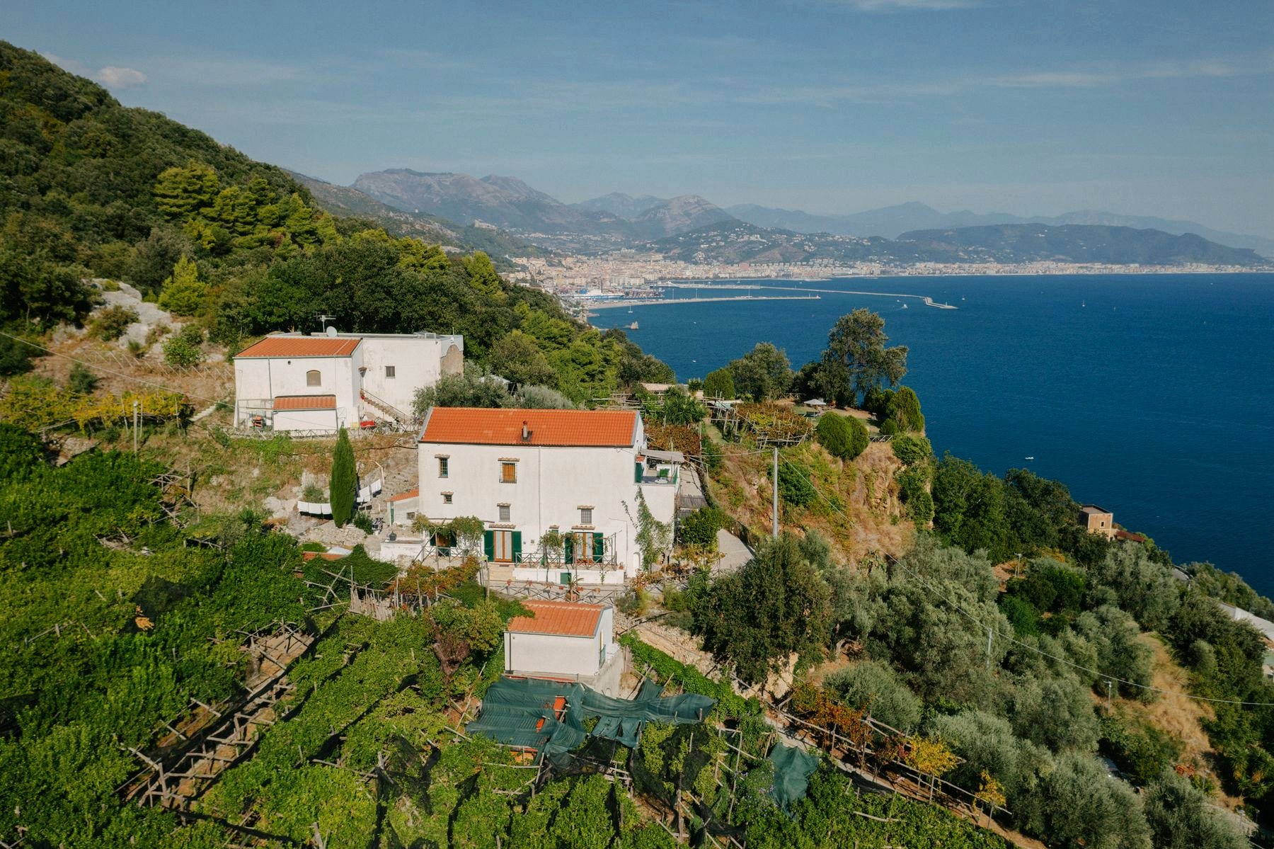 Veduta aerea della casa tra i terrazzamenti di limoni, con il Golfo di Salerno sullo sfondo
